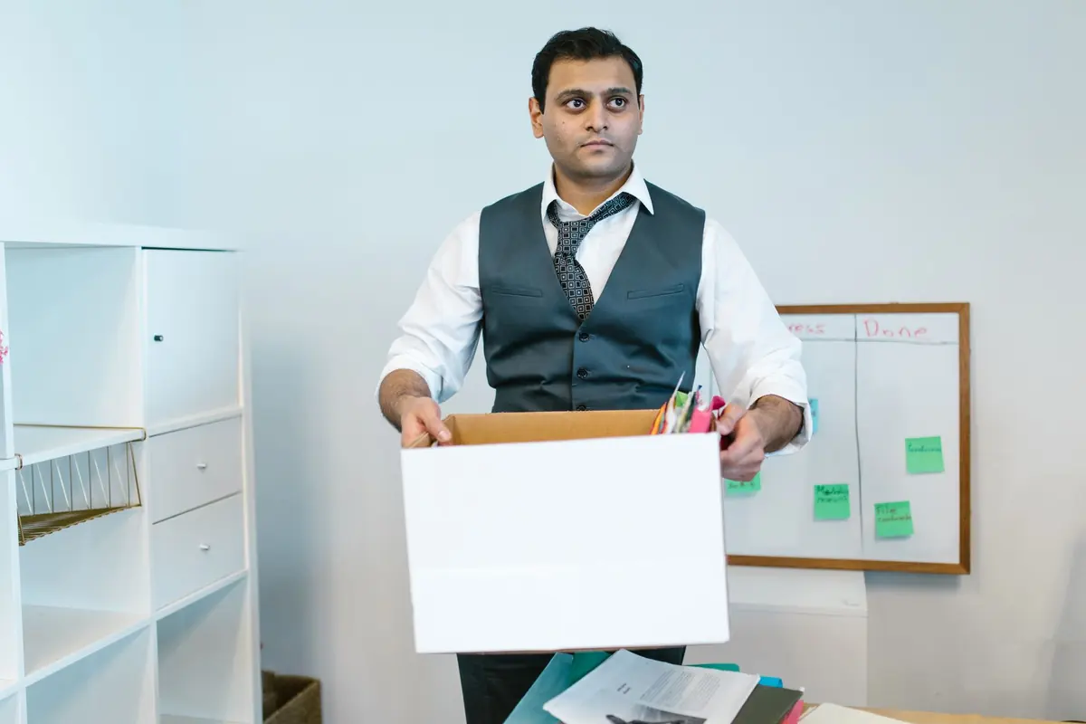 Ein Mitarbeiter trägt einen Karton zwischen Büroregalen