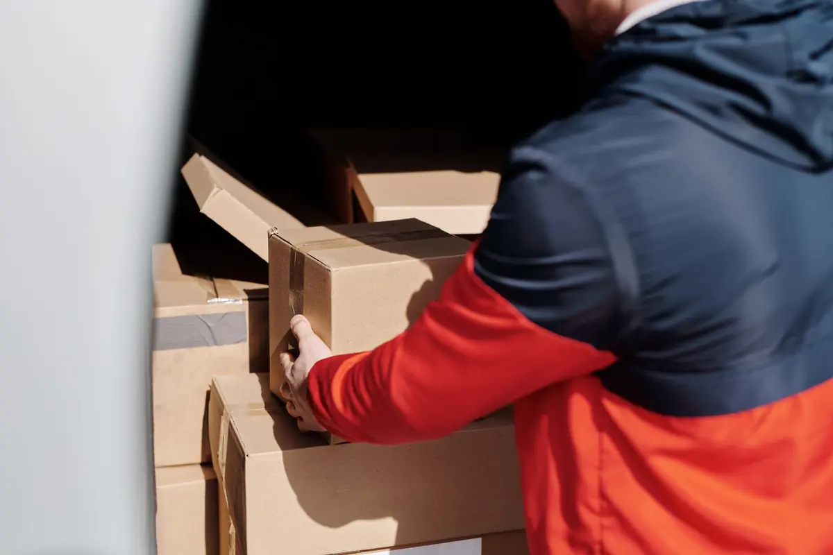 Ein Helfer lädt Kartons am Heck eines Transporters ein