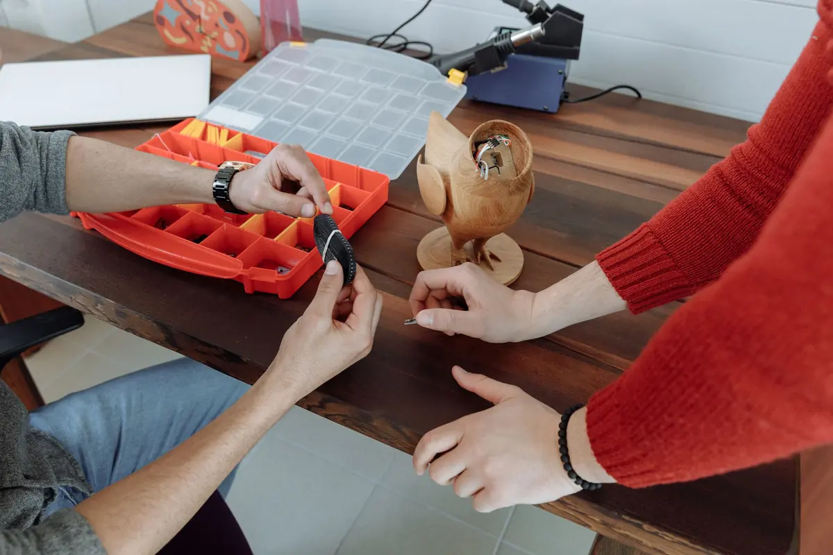 Hände ordnen kleine Möbelteile in einer Sortierbox