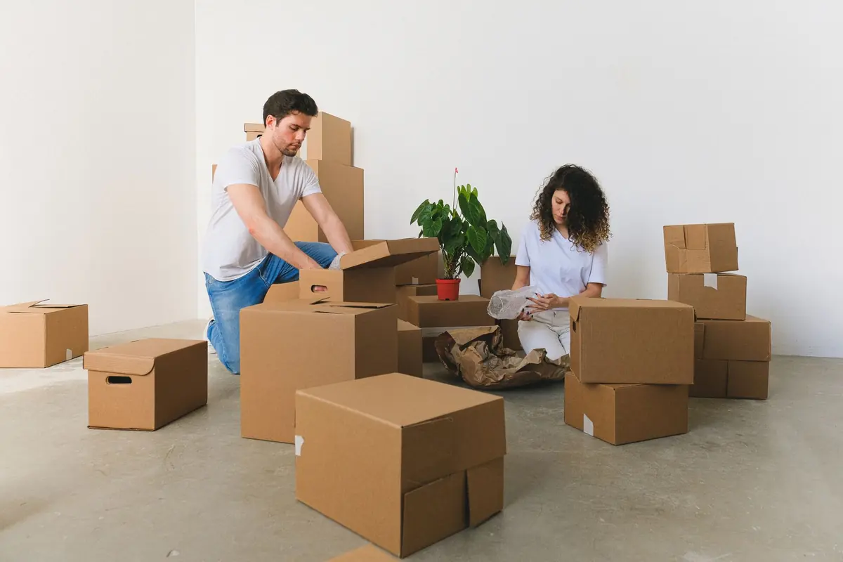 Zwei Personen packen Hausrat zwischen mehreren Kartons