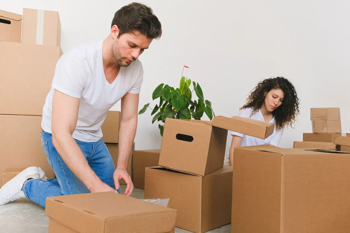 Zwei Personen packen gemeinsam Kartons in einer neuen Wohnung aus