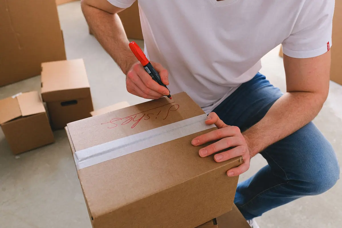 Ein gepackter Karton wird mit breitem Klebeband verschlossen