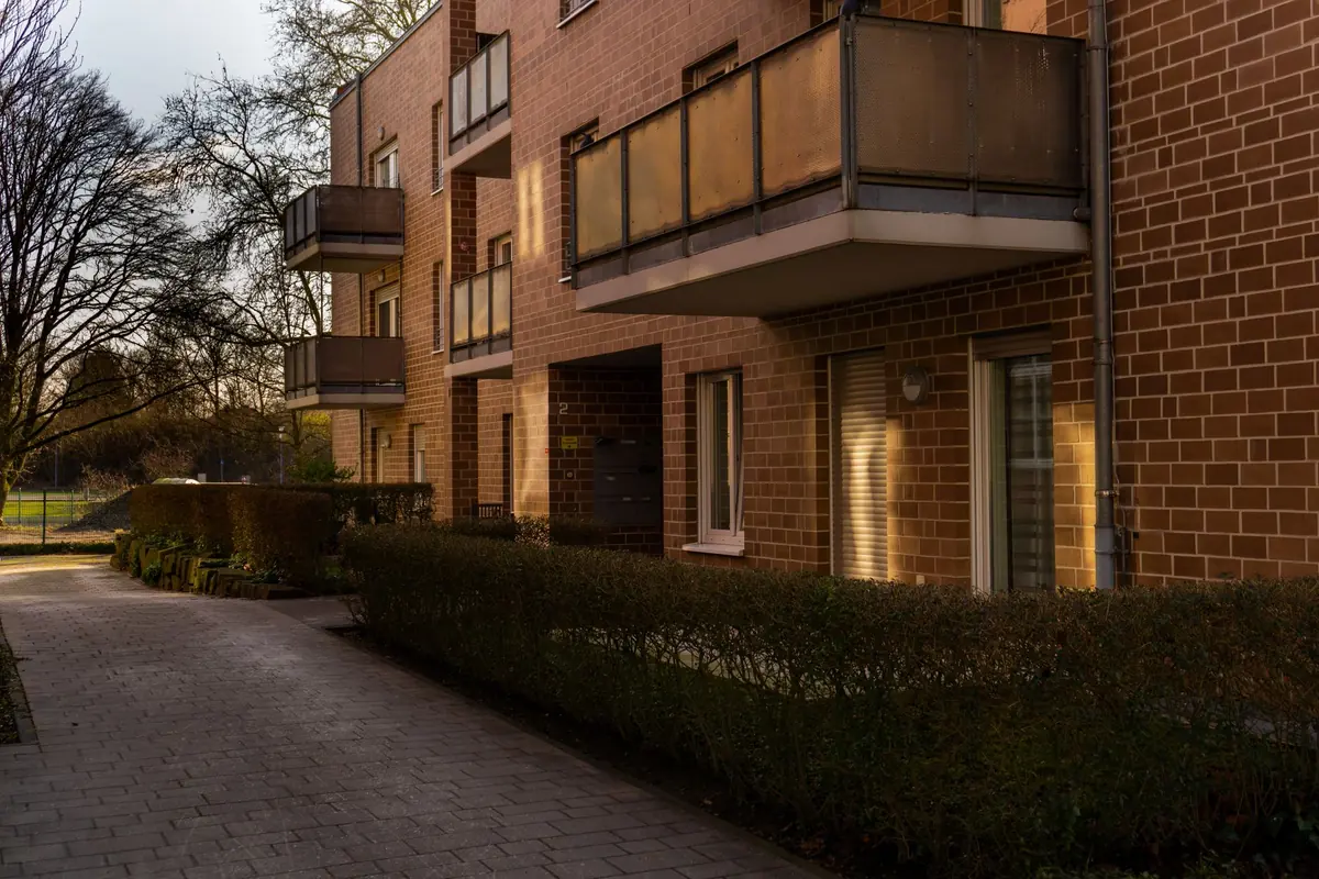 Der Zugang zu einem Mehrfamilienhaus führt über einen befestigten Weg