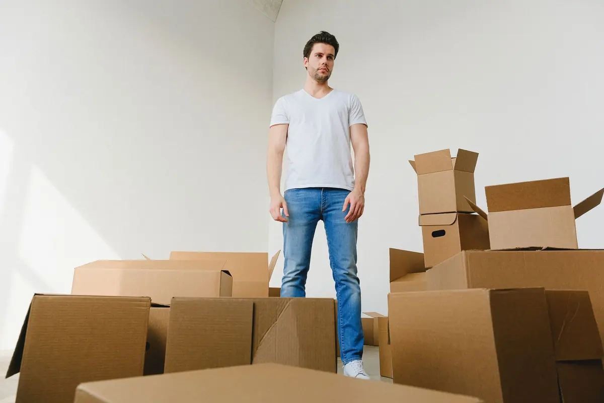 Ein Mann steht zwischen gepackten Kartons in einem hellen Zimmer