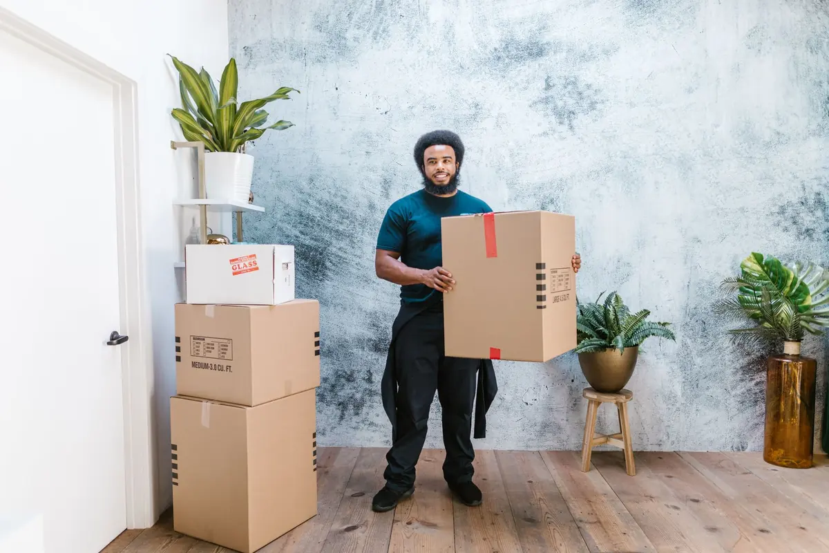 Ein Helfer trägt einen großen Karton durch eine Wohnung