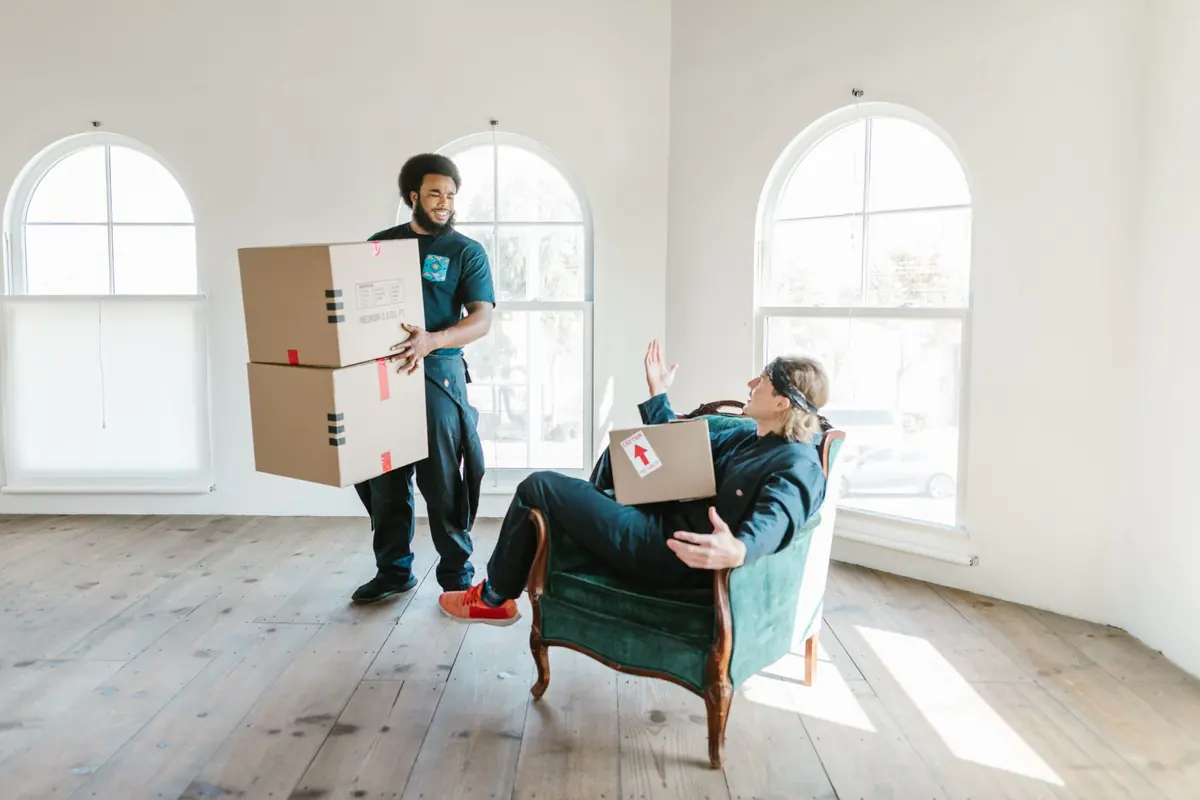 Zwei Helfer bewegen gepackte Kartons durch einen hellen Raum